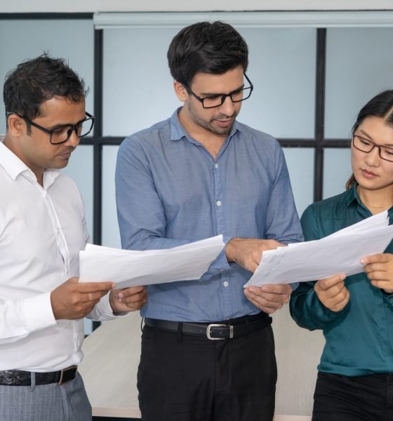 Multiethnic business team analyzing financial reports. Smart experts presenting papers to group leader. Teamwork and analysis concept