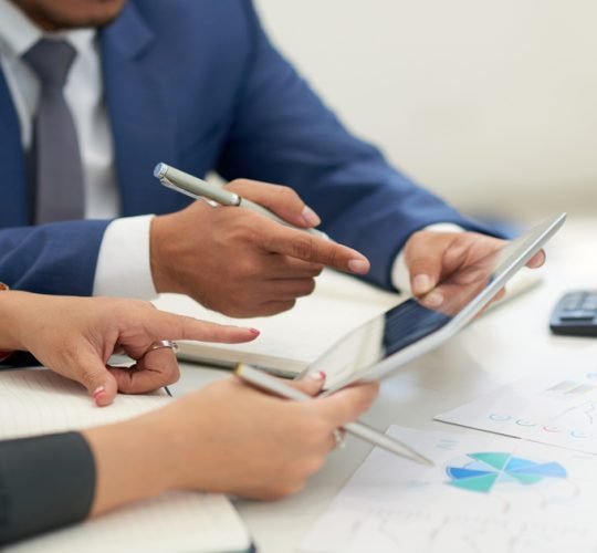 business-people-sitting-meeting-with-charts-looking-pointing-tablet